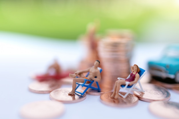 Foto miniatura pessoas sentadas na praia com moedas