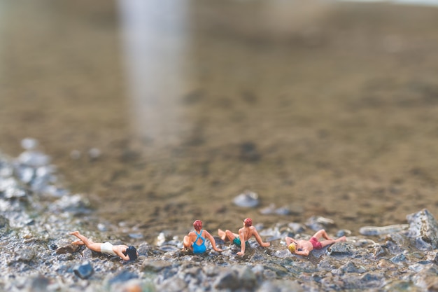 Miniatura pessoas vestindo maiô relaxante na praia