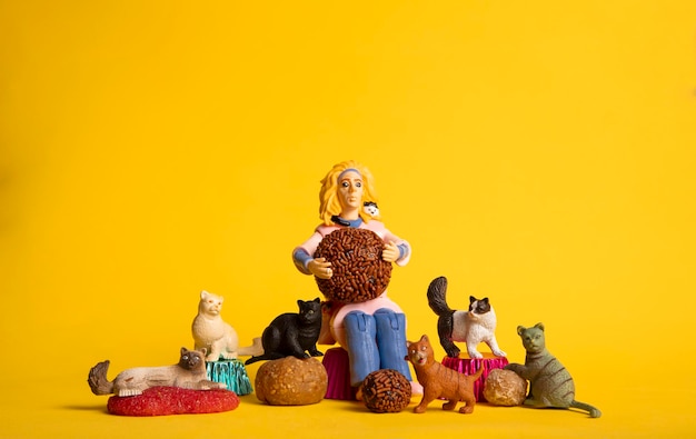 Foto miniaturas de brinquedo de uma menina e gatos em fundo amarelo