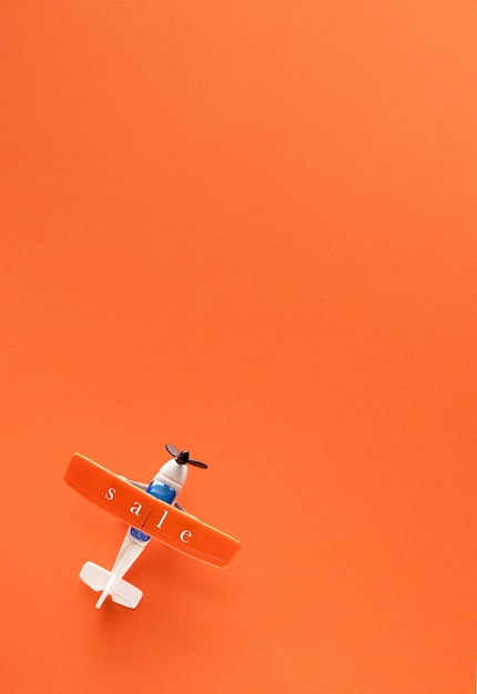 Miniaturflugzeug mit der Aufschrift Verkauf auf orangefarbenem Hintergrund und Platz für Text