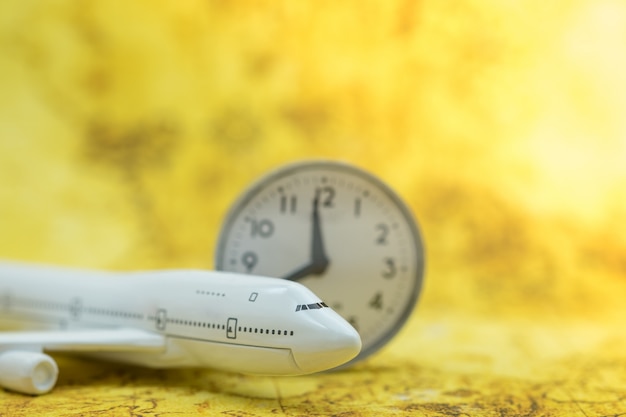 Miniaturflugzeugspielzeugmodell mit runder Uhr der Weinlese auf Weltkarte.
