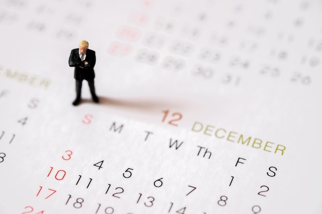 Miniaturgeschäftsgehaltsleute stehen am Dezember der letzte Monat des Jahresende.