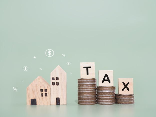 Foto miniaturhaus holzblöcke mit dem wort tax und einem stapel münzen das konzept der zahlung von steuern für das haus immobilieninvestitionen haushypotheken immobilien