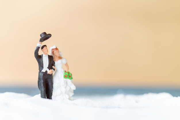 Miniaturleute Glückliches Hochzeitspaar am weißen Strand, Hochzeitskonzept