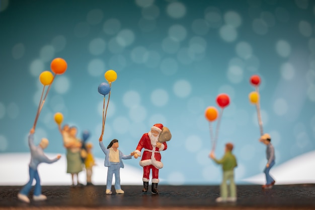 Miniaturleute: Weihnachtsmann und Kinder, die Ballon halten