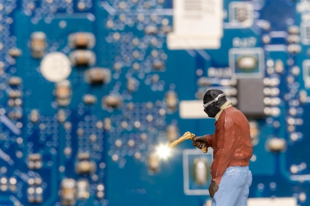Miniaturmenschen Computerreparaturtechniker reparieren eine elektronische Platine mit Gas