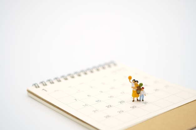 Miniaturmenschen, die auf weißem Kalender stehen