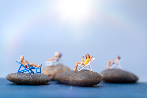 Miniaturmenschen, die sich am Strand sonnen, Sommerzeitkonzept