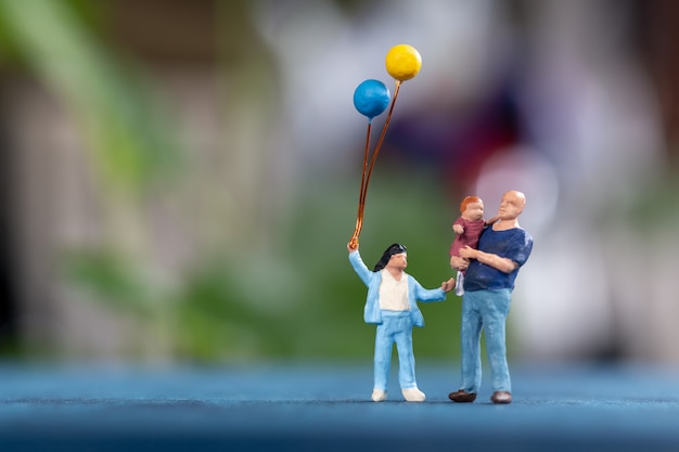 Miniaturmenschen: Glückliche Familie, die Ballon im Park hält