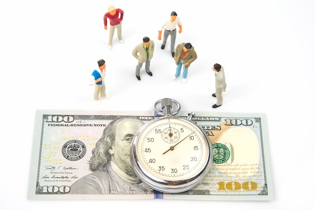 Miniaturmenschen mechanische Stoppuhr auf dem Hintergrund von Dollars und Geschäftsleuten Teilzeitgenauigkeit für Geschäfts- und Finanzzeit
