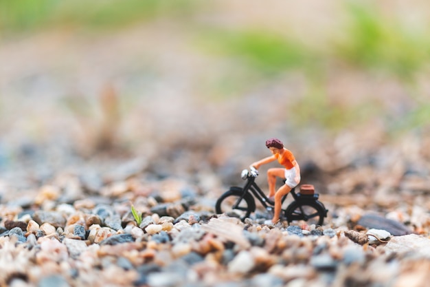 Miniaturmenschen: Reisende, die auf dem Sand Fahrrad fahren