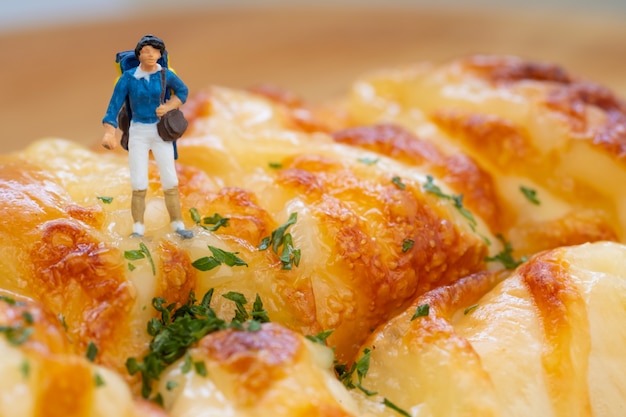 Foto miniaturmenschen: rucksacktouristen, die auf wurstbrot gehen.