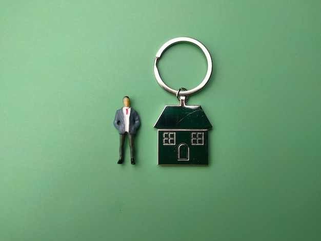 Miniaturmenschen und Hausschlüsselbund auf grünem Hintergrund Das Konzept, ein neues Zuhause zu bekommen