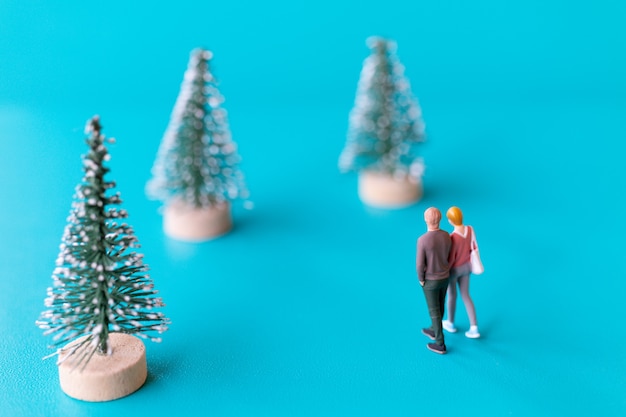 Miniaturmenschen, verliebtes Paar, das neben einem Weihnachtsbaum steht, Weihnachten und ein glückliches neues Jahr-Konzept.