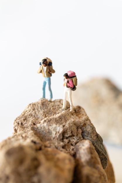Miniaturmenschen, Wanderer mit Rucksäcken, die auf einem Berg stehen, Abenteuerkonzept