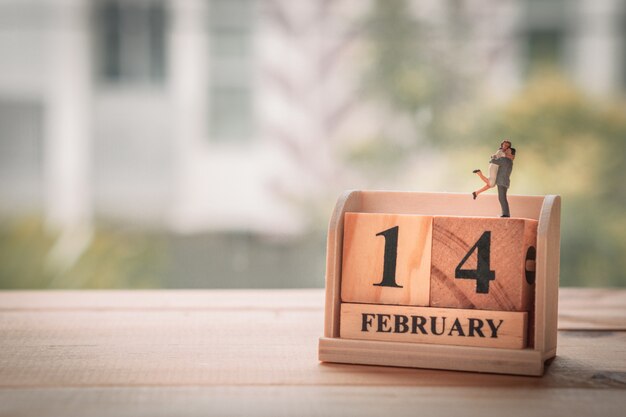 Miniaturpaar mit hölzernem Kalender. 14. februar. Valentinstag.