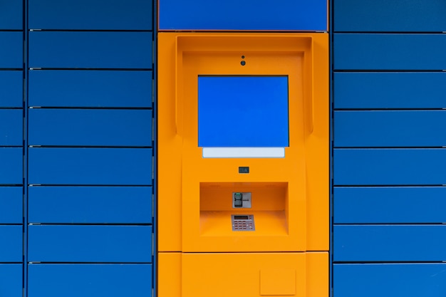 Minibank de caja naranja con pantalla de copyspace en blanco sobre fondo de panel azul