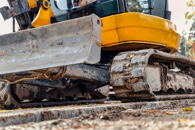 Foto miniexcavadora de primer plano durante la construcción de un complejo residencial moderno equipos de construcción en miniatura para trabajar en condiciones de hacinamiento