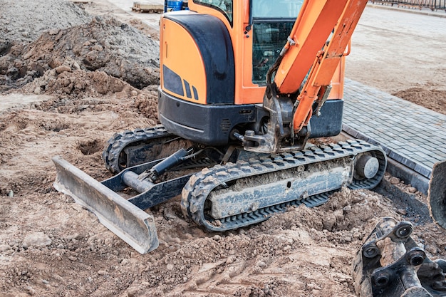 Miniexcavadora en el sitio de construcción. Equipo de construcción compacto para movimiento de tierras.