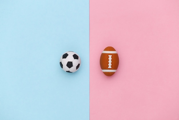 Minifußball und Rugbyball auf einem blau-rosa Pastellhintergrund. Minimalismus Sportkonzept. Ansicht von oben. Flach legen