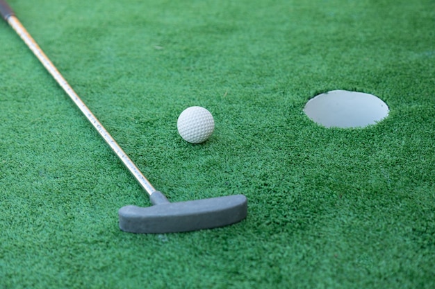 Minigolfausrüstung, Golfschläger, Ball und Loch auf grünem Grund