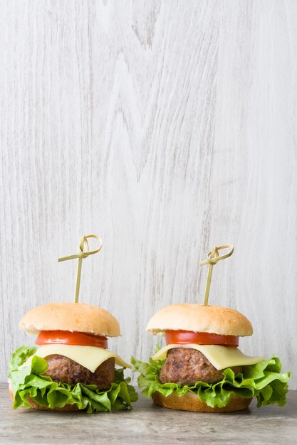 Minikäseburger mit Gemüse auf Holztischkopienraum