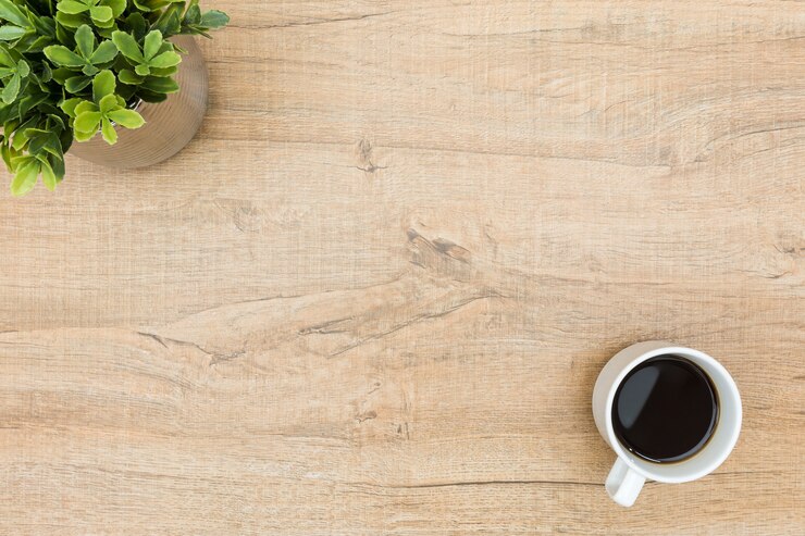 Foto mínima mesa de madeira com café e uma planta pequena.
