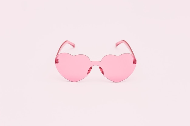 Minimale Modefotografie mit herzförmiger Brille auf Rosa