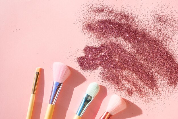 Foto minimale moderne kosmetikszene mit einem satz von make-up-bürsten auf rosa hintergrund mit glitter und schattenüberlagerung