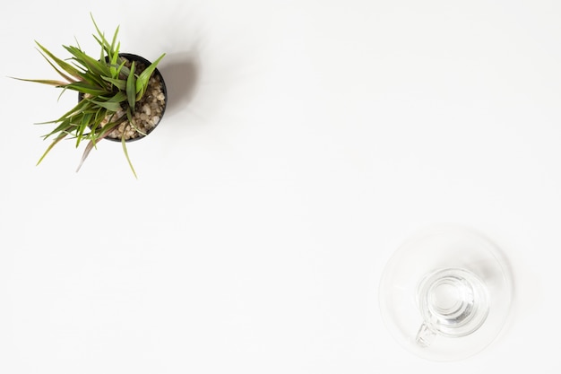 Minimale weiße Schreibtischtabelle mit Glas des Trinkwasser- und Graspotentiometers. Draufsicht mit Kopienraum, flache Lage.