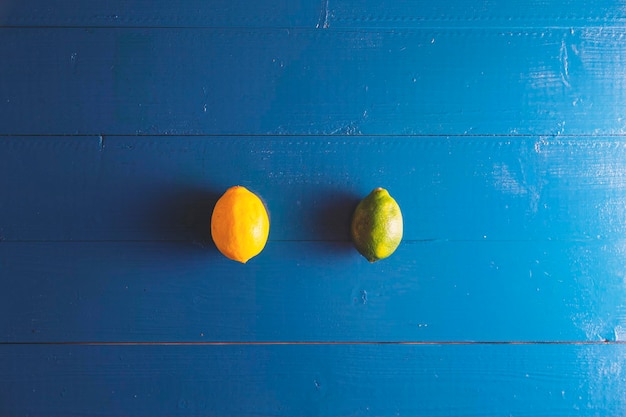 Minimaler Flachblick auf Limettenzitrone über blauem Vintage-Hintergrund mit Kopierraum