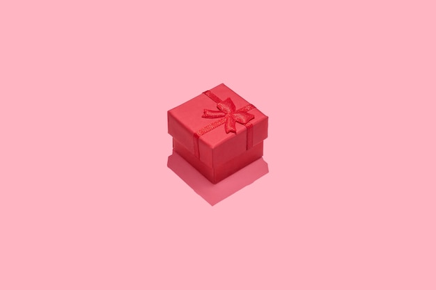 Minimaler Kompositionshintergrund mit roter Geschenkbox auf rosa Hintergrund.