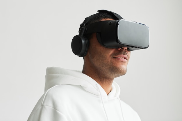 Minimales Porträt des modernen Mannes mit VR-Headset vor weißem Hintergrund, Kopierraum