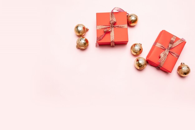Minimales Weihnachtsneujahrskonzept von Weihnachtsroten Geschenkboxen, Bälle auf Pastellrosahintergrund. Minimales Konzept des neuen Jahres.