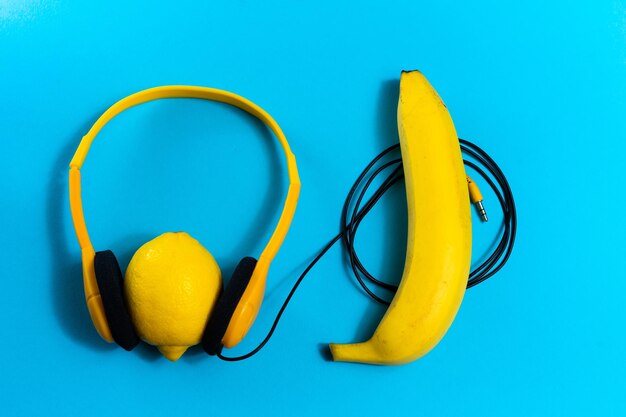 Minimalismo conceito de colocação plana ouve música fones de ouvido banana em fundo azul vista superior