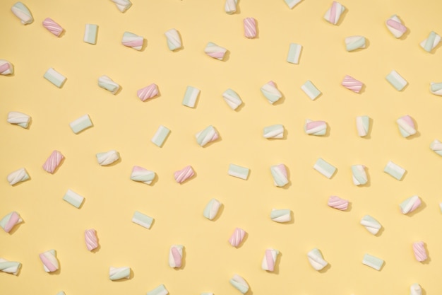 Minimalismo de marshmallows doces em fundo amarelo palha pastel