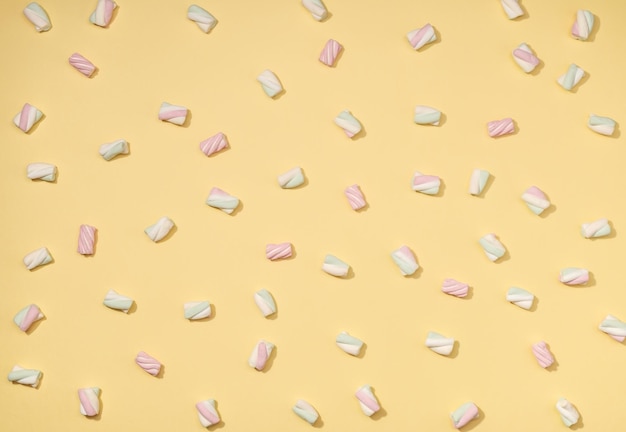 Minimalismo de marshmallows doces em fundo amarelo palha pastel