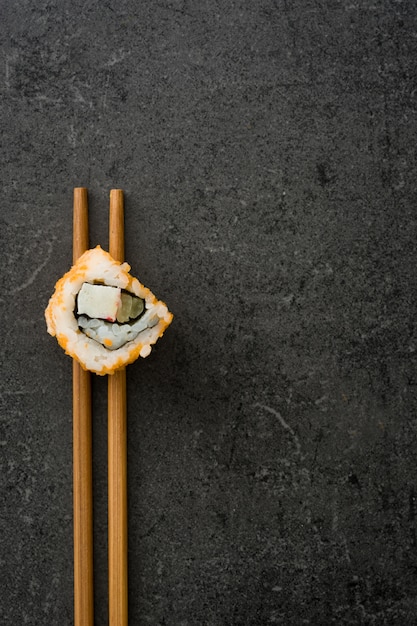 Minimalista sushi de comida japonesa con palillos en la vista superior de pizarra negra