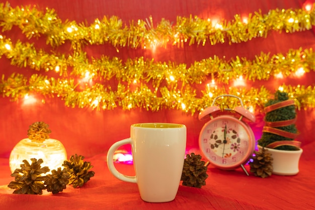 Minimalistische Konzeptidee, die Produkte anzeigt. Kaffeetasse auf Weihnachten und Neujahr background.red, Lichter, Kiefernblumen