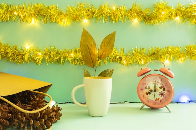 Minimalistische Konzeptidee, die Produkte anzeigt. Kaffeetasse auf Weihnachten und Neujahr Hintergrund. Wecker. Kiefernblume