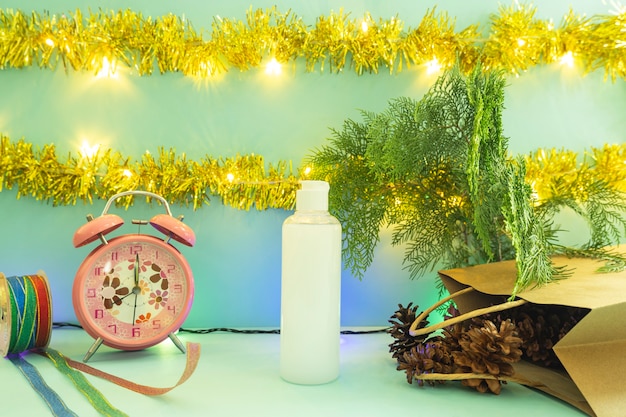 Minimalistische Konzeptidee, die Produkte anzeigt. kosmetische flaschen auf weihnachten und neujahrshintergrund. Wecker. Kiefernblume
