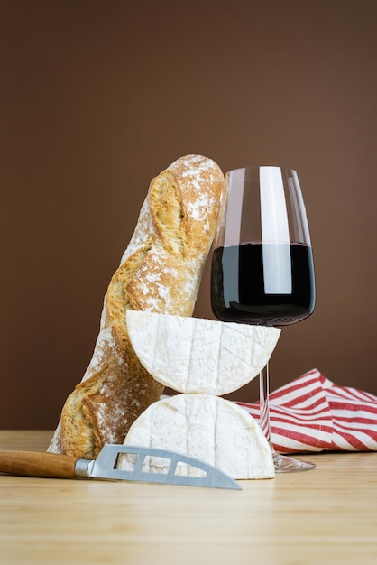Minimalistische Zusammensetzung aus einem Glas Rotwein, einer Baguette und Camembert-Käse