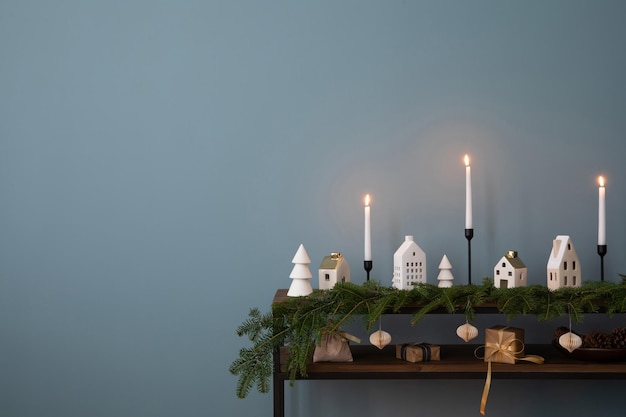 Foto minimalistische zusammensetzung von weihnachtsinterieur mit kopierraum holzkonsole mit verstuckung weihnachtenkugeln kerze mit kerzenstange blaue wandgeschenke und persönliche accessoires hausdekoration vorlage