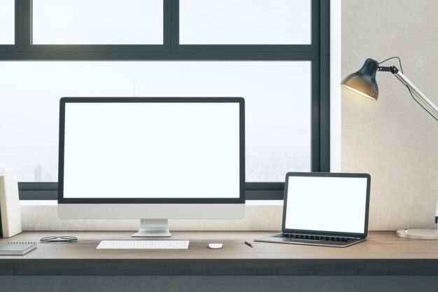 Minimalistischer Designer-Desktop mit leerem weißem Computer- und Laptop-Bildschirm