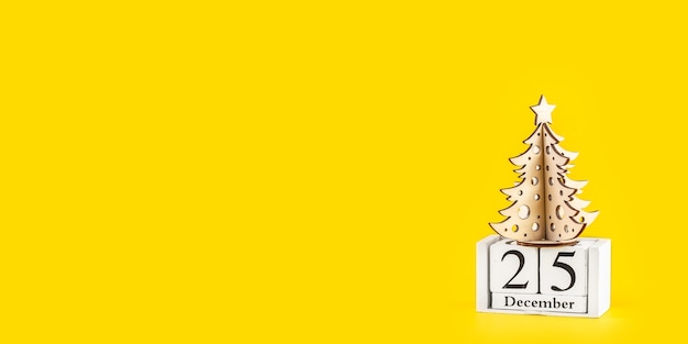 Minimalistischer Weihnachtsbaum auf gelbem Pastelltrendhintergrund. Frohe Weihnachten und ein gutes neues Jahr Grußkarte mit Kopienraum. Winterferienkonzept. Langes breites Banner.