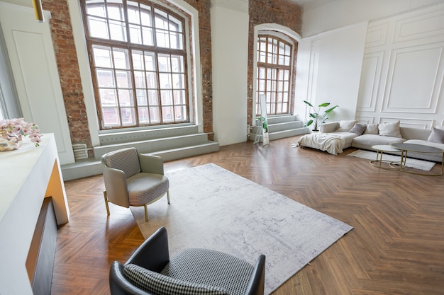 Foto minimalistisches interieur einer ultramodernen großraumwohnung mit weißen und grauen wänden mit relief und grauen, stilvollen polstermöbeln und riesigen fenstern