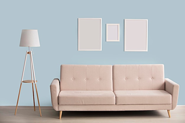 Minimalistisches Interieur Sofa-Lampen-Bilderrahmen auf blauem Wandhintergrund