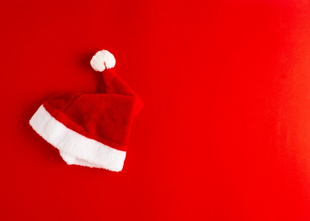 minimalistisches Konzept der Weihnachtsmann-Weihnachtsmannmütze auf Rot