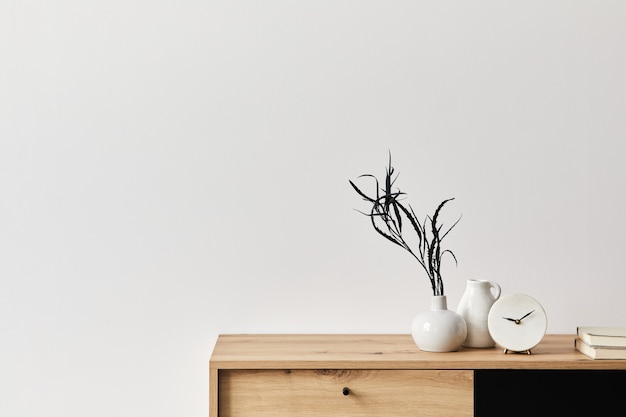 Minimalistisches konzept der wohnzimmereinrichtung in eleganter wohnung mit holzkommode, blatt in keramikvase, uhr und eleganten persönlichen accessoires in moderner wohnkultur. platz kopieren.. .