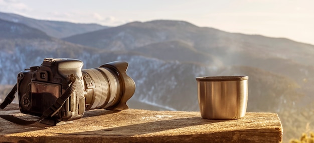 Minimalistisches Stillleben in den Bergen Panoramakamera und dampfende Becherthermosflasche mit heißem Tee